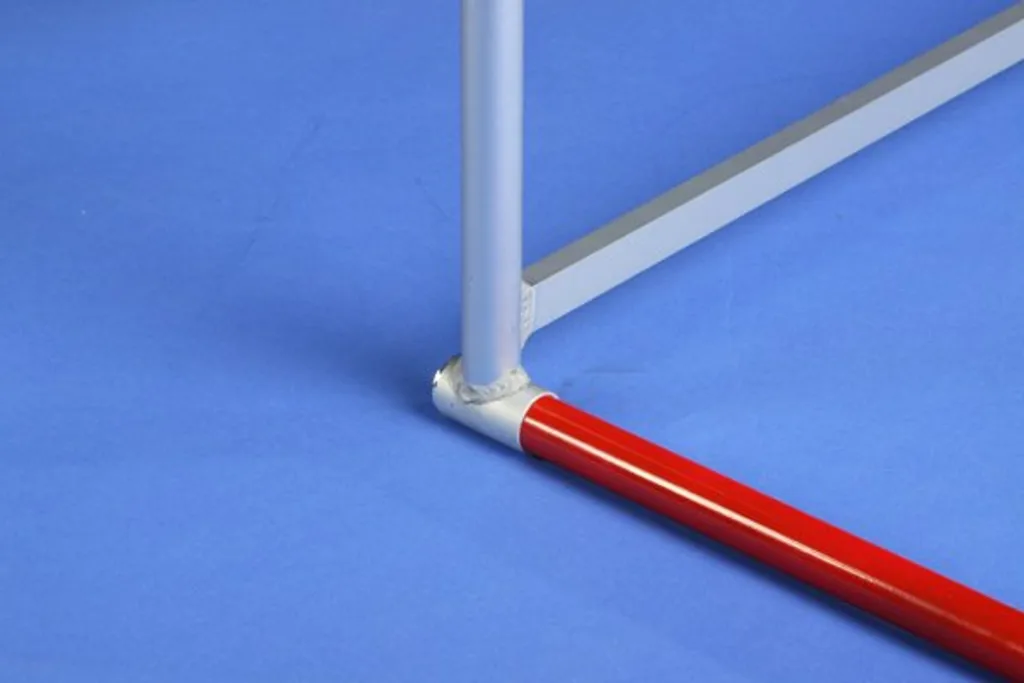 Steel and aluminium hurdle base with welded vertical leg and a red crossbar on a blue surface.