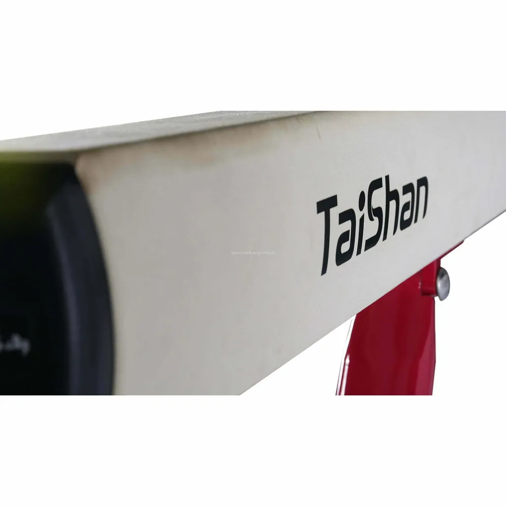 Red competition balance beam with padded top labeled Taishan and a red adjustable leg visible.