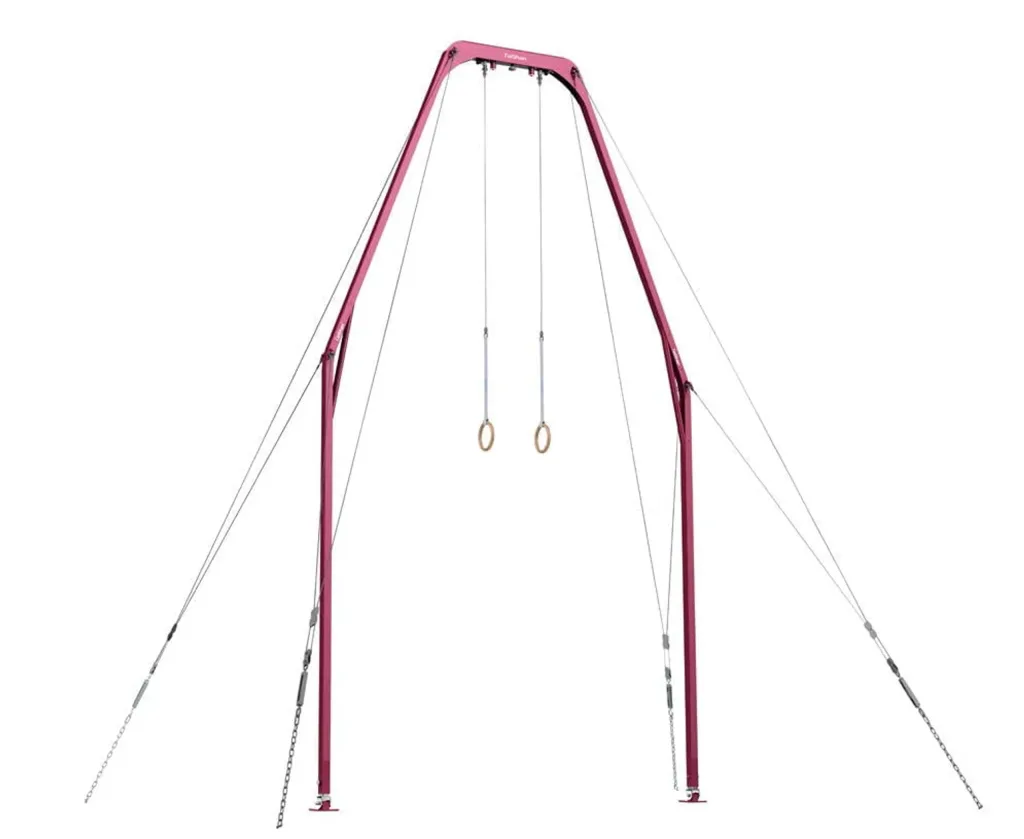 Red freestanding gymnastics frame with two composite wood rings suspended by steel cables and anchored with guy wires.