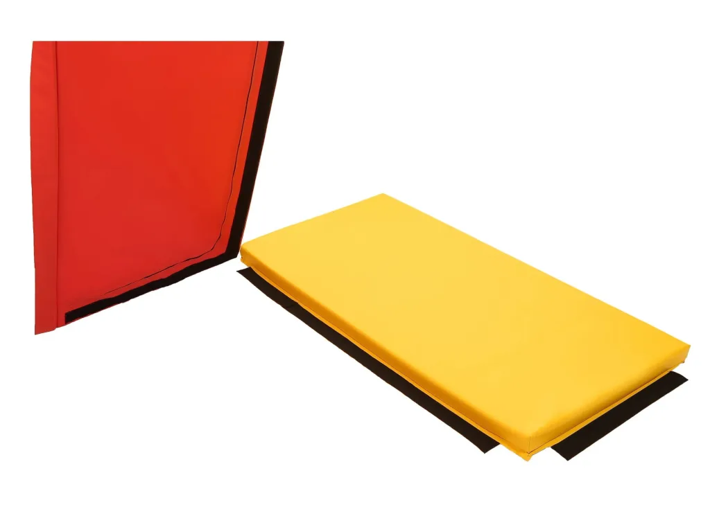 Yellow PVC rectangular tumble mat with black velcro flaps next to a standing red PVC mat cover.